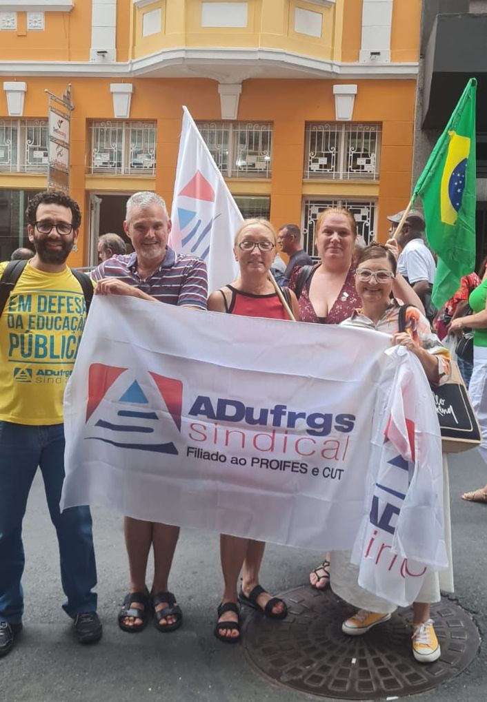 Diretores e professores filiados seguram bandeira da ADUFRGS durante ato em frente ao Sindibancários